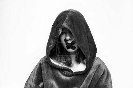 Foto de Chica con una boca sellada en una sudadera con una capucha sobre un fondo aislado, estar en silencio y no decir nada, un secreto - Imagen libre de derechos