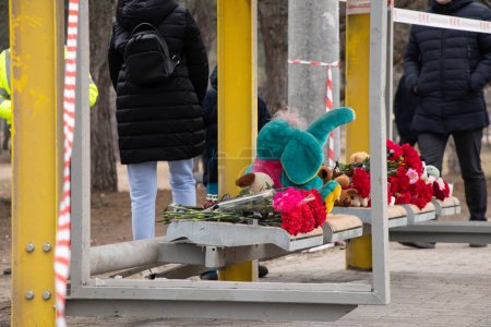 Téléchargez les photos : Toys and flowers lie at a trolleybus stop next to a house blown up by a Russian rocket on Pobeda in the city of Dnepr in Ukraine during the war, the memory of those who died - en image libre de droit