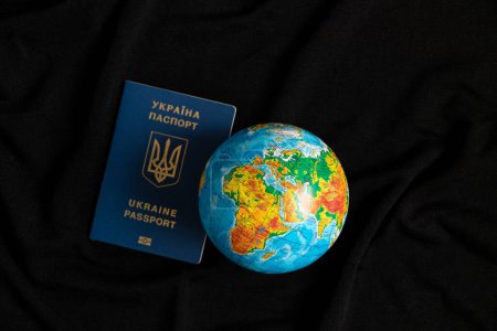 Foto de Globo y pasaporte extranjero ucraniano biométrico en un fondo negro, viajes - Imagen libre de derechos