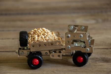 Photo for Cargo transportation of grain on a children's typewriter truck made of a metal constructor on a wooden board, logistics, transportation of grain - Royalty Free Image
