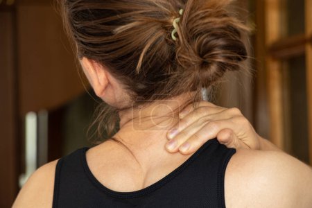 A young girl holds her hand on her neck from back pain at home,back pain