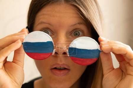 Téléchargez les photos : Drapeau de la Russie sur les lunettes d'une fille, aveugle et trompé par la propagande russe, ne voit rien à cause de la propagande - en image libre de droit