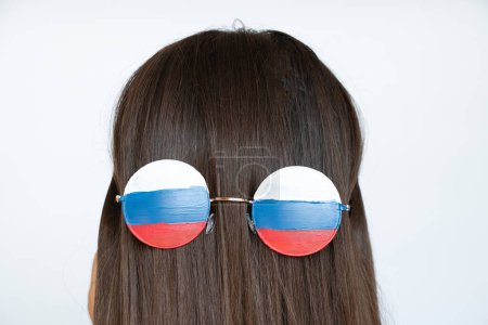Téléchargez les photos : Le drapeau de la Russie sur les lunettes d'une jeune fille avec le dos sur les cheveux, aveugle et trompé par la propagande russe, ne voit rien à cause de la propagande - en image libre de droit