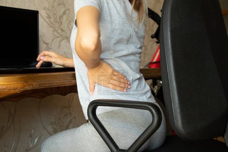 Photo for Woman with back and spine pain sitting at computer chair at home while working, Medical concept, spine support, back pain - Royalty Free Image