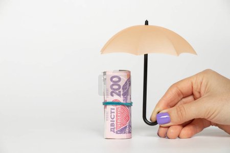 Téléchargez les photos : 200 hryvnia sous un petit parapluie dans la main d'une fille sur un fond blanc, affaires et finances en Ukraine, économie - en image libre de droit