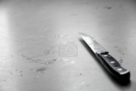 Photo for A wet, dirty kitchen knife lies on a light table in the light from the window, kitchen and knife on the table - Royalty Free Image