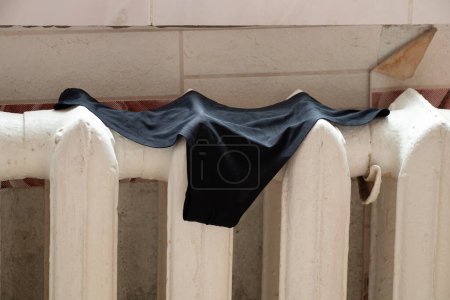 Photo for Women's black panties hang on an old cast iron radiator in the apartment and dry, underwear to dry - Royalty Free Image