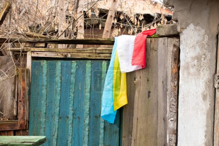 Foto de La bandera de Ucrania y Polonia cuelga en la pared de una antigua casa destruida en Ucrania en el Dniéper - Imagen libre de derechos