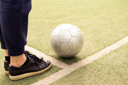 Las piernas de las mujeres en un campo de fútbol y una pelota de fútbol gris en Ucrania, jugando fútbol en el patio, deporte