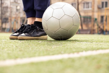 Frauenbeine auf einem Fußballplatz und ein grauer Fußball in der Ukraine, Fußball spielen auf dem Hof, Sport