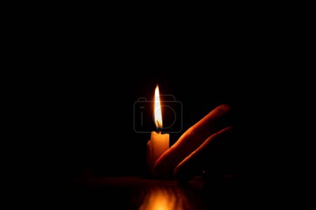 Téléchargez les photos : Les mains des femmes près d'une flamme de bougie dans l'obscurité, la foi et la religion, priant - en image libre de droit