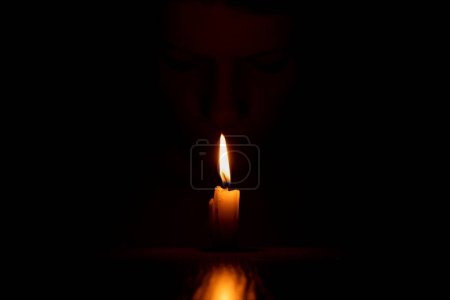 Das Gesicht eines ukrainischen Mädchens im Dunkeln mit einer Kerze, einer Kerzenflamme und einem Mädchen