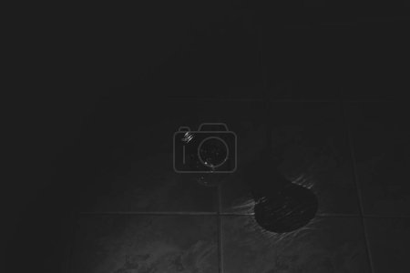 Una lámpara incandescente cuelga de una cuerda en la oscuridad y las sombras en la pared, foto en blanco y negro