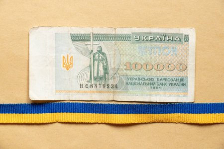 One hundred thousand Ukrainian Carbonates and a ribbon of the Ukrainian flag blue on brown paper, the money of Ukraine
