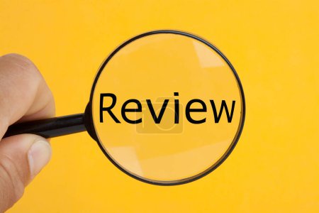Hand holding magnifying glass over the word review.