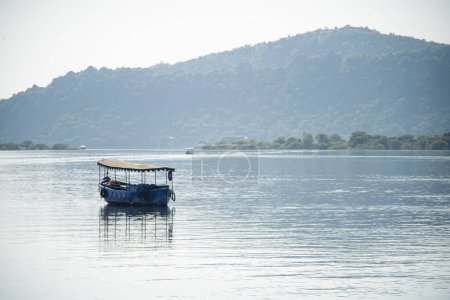 Photo for Abandoned boat adrift marooned in the middle of water of lake pichola surrounded by aravalli hills in tourist city of udaipur rajasthan India - Royalty Free Image
