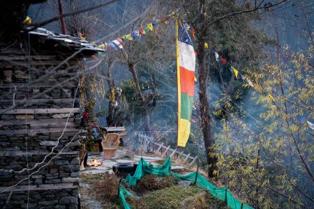 Foto de Sacred religious multicolored prayer flags old and tattered torn outside wooden cabin in bhuddist prayer incantation common in hill stations in Himachal Pradesh India - Imagen libre de derechos