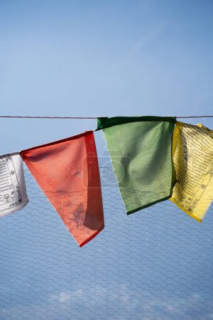 Téléchargez les photos : Drapeaux religieux sacrés de prière multicolores sur la clôture se déplaçant dans le vent montrant une incantation de prière bhuddiste commune dans les stations de colline en Himachal Pradesh Inde - en image libre de droit