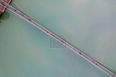 Foto de Recta hacia abajo decreciente dron aéreo disparo de puente colgante ram setu sobre las aguas azules que fluyen rápido de ganga en la ciudad santa de Rishikesh India - Imagen libre de derechos