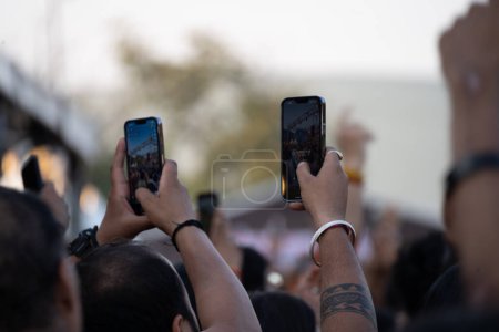 Showing people throwing up hands and recording event through mobile phones enjoying a party, DJ, concert or festival India
