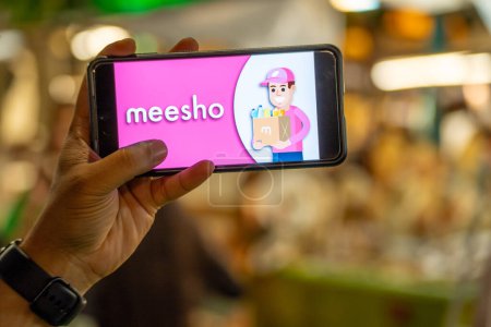 Photo for Delhi, India - 2nd Apr23 : woman holding mobile phone showing indian social commerce startup Meesho logo at an event - Royalty Free Image