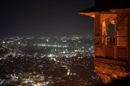 Foto nocturna que muestra el balcón de la terraza del fuerte de Mehrangarh con vistas a las luces de la ciudad de Jodhpur en la India