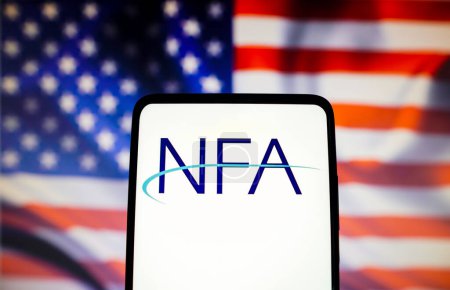 Foto de 13 de noviembre de 2022, Brasil. En esta ilustración fotográfica, el logotipo de la Asociación Nacional de Futuros de los Estados Unidos (NFA) se muestra en una pantalla de teléfono inteligente con una bandera de los Estados Unidos en el fondo - Imagen libre de derechos