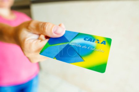 Foto de January 6, 2023, Brazil. In this photo illustration, a woman shows the Citizen Card, from Caixa Econmica Federal. Document was created by the Brazilian federal government in order to unify the functional accounts to which workers are entitled. - Imagen libre de derechos
