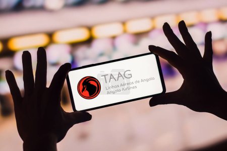 Téléchargez les photos : January 19, 2023, Brazil. In this photo illustration, the TAAG Linhas Areas de Angola logo is displayed on a smartphone screen. It is the national airline of Angola, having its headquarters in Luanda. - en image libre de droit