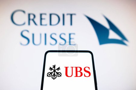 Photo for March 20, 2023, Brazil. In this photo illustration the UBS logo seen displayed on a smartphone and Credit Suisse logo on the background - Royalty Free Image