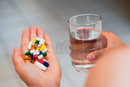 Téléchargez les photos : 11 avril 2023, Brésil. Dans cette illustration photo, une personne tenant plusieurs pilules médicinales et un verre d'eau. - en image libre de droit