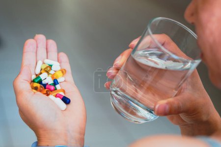 Téléchargez les photos : 11 avril 2023, Brésil. Dans cette illustration photo, une personne tenant plusieurs pilules médicinales et un verre d'eau. - en image libre de droit