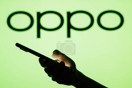 Photo for June 13, 2023, Brazil. In this photo illustration the OPPO logo seen in the background of a silhouette woman holding a mobile phone - Royalty Free Image