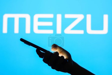 Photo for June 13, 2023, Brazil. In this photo illustration the Meizu logo seen in the background of a silhouette woman holding a mobile phone - Royalty Free Image