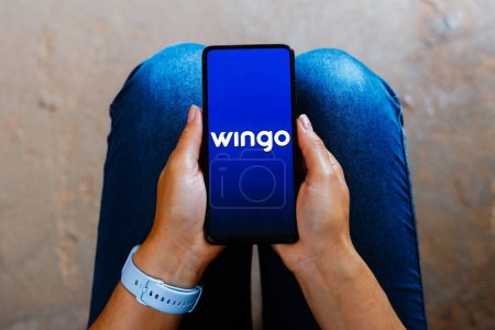 Foto de 16 de junio de 2023, Brasil. En esta ilustración fotográfica, el logotipo de Wingo se muestra en la pantalla de un teléfono inteligente - Imagen libre de derechos