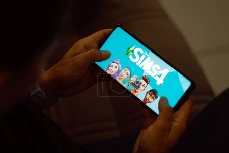 Foto de 10 de julio de 2023, Brasil. En esta ilustración fotográfica, el logotipo de Sims 4 se muestra en la pantalla de un teléfono inteligente - Imagen libre de derechos