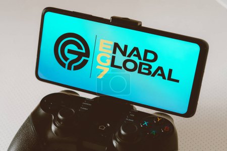 Téléchargez les photos : 14 août 2023, Brésil. Dans cette illustration photo, le logo Enad Global 7 AB (EG 7) affiché sur un écran de smartphone, connecté à un joystick de jeu - en image libre de droit