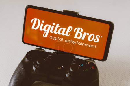 Photo for August 14, 2023, Brazil. In this photo illustration, the Digital Bros logo displayed on a smartphone screen, connected to a gaming joystick - Royalty Free Image