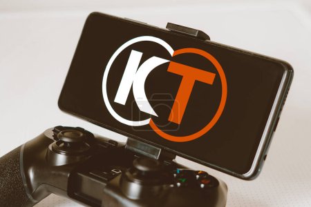 Photo for August 14, 2023, Brazil. In this photo illustration, the Koei Tecmo logo displayed on a smartphone screen, connected to a gaming joystick - Royalty Free Image