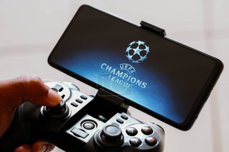 Foto de 15 de agosto de 2023, Brasil. En esta ilustración fotográfica, una persona juega en un joystick de juego y el logotipo de la UEFA Champions League (UCL) se muestra en la pantalla de un teléfono inteligente - Imagen libre de derechos