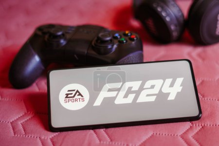 Foto de 9 de octubre de 2023, Brasil. En esta ilustración fotográfica, el logotipo de EA SPORTS FC 24 se muestra en la pantalla de un smartphone, junto a un mando - Imagen libre de derechos