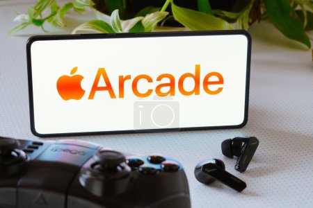 Photo for October 25, 2023, Brazil. In this photo illustration, the Apple Arcade logo is displayed on a smartphone screen, next to a gamepad and headphones - Royalty Free Image