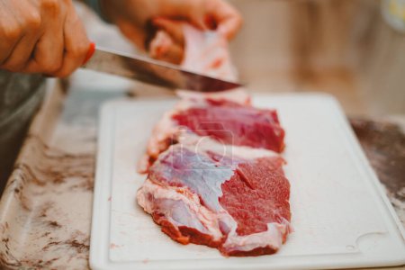 Foto de La grasa de la carne roja es quitada por el cocinero. La carne roja tiene una gran cantidad de vitaminas del complejo B, E, K y zinc, hierro, proteínas - Imagen libre de derechos