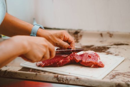 Téléchargez les photos : La graisse de la viande rouge est retirée par le cuisinier. La viande rouge contient une énorme quantité de vitamines du complexe B, E, K et zinc, fer, protéines - en image libre de droit