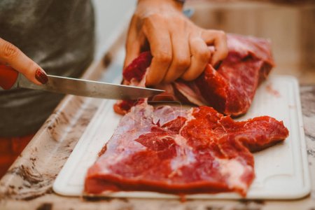 Photo for Cook preparing red meat for the barbecue. Barbecue is a delicacy made from fresh or processed meat, roasted over a fire or coals, using skewers or grills - Royalty Free Image