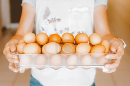 Téléchargez les photos : Gros plan d'une femme tenant un plateau d'œufs rouges en liberté. L'œuf a des nutriments à action antioxydante tels que les caroténoïdes, les vitamines A et E, l'acide folique, le zinc, le magnésium et le sélénium. - en image libre de droit