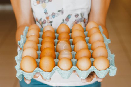 Foto de Acercamiento de una mujer sosteniendo una bandeja de huevos rojos de corral. El huevo tiene nutrientes con acción antioxidante como carotenoides, vitamina A y E, ácido fólico, zinc, magnesio y selenio. - Imagen libre de derechos