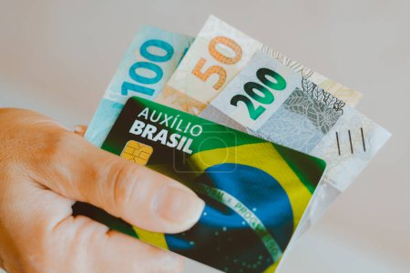 Téléchargez les photos : 17 janvier 2024, Brésil. Sur cette photo, une femme tenant la carte Auxlio Brasil (Bolsa Famlia) avec des billets en argent réel du Brésil. - en image libre de droit