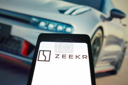 Photo for January 29, 2024, Brazil. In this photo illustration, the Zeekr logo is displayed on a smartphone screen and in the background, an electric car from the brand - Royalty Free Image