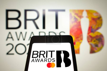 Foto de 28 de febrero de 2024, Brasil. En esta ilustración fotográfica, el logotipo de los Brit Awards se muestra en la pantalla de un teléfono inteligente y en el fondo. - Imagen libre de derechos